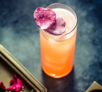 A photo of a cocktail in a tall glass with heart shaped garnishes.